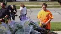 Luciano Antonini, 12, pays his respects to two court bailiffs, both former policemen, who were shot and killed by an inmate in Michigan. (Associated Press)